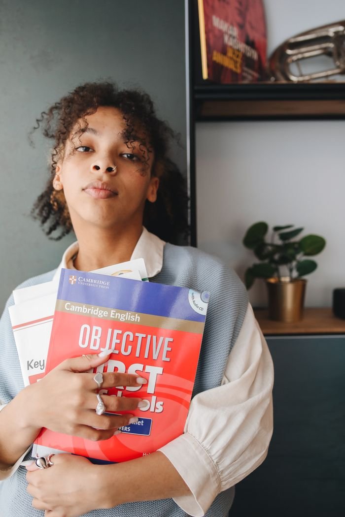 Student holding English study guides in an indoor setting, showcasing pensive expression.
